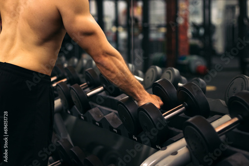 shirtless strong man lifting dumbbell in a gym photo