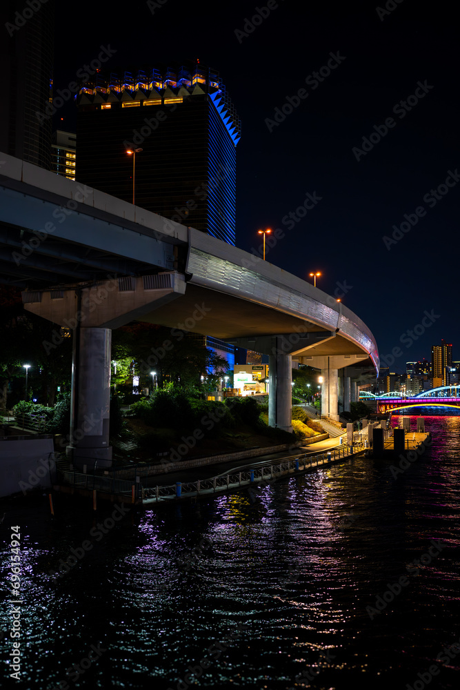 elevated expressway in tokyo wrapping alongside the sumida river and buildings