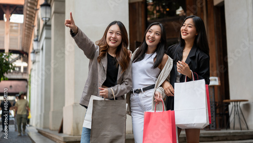 Group of fun Asian girl friends are enjoying shopping in the city during their abroad trip together. photo