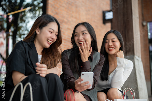Group of happy young Asian girls are enjoying chit chat while resting on the stairs after shopping. photo