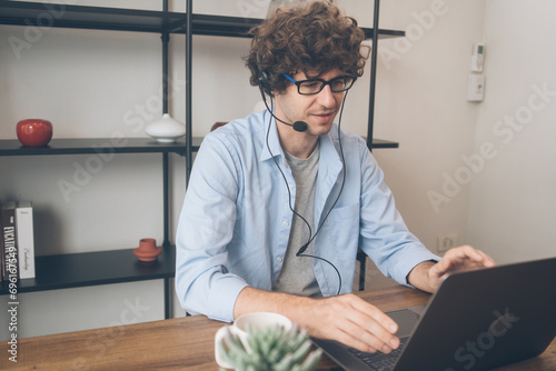 Male agent or telemarketing in eyeglasses with headphone talking to customer working at home. Man meeting video call work remotely on weekend. Teacher teaching or consulting online.
