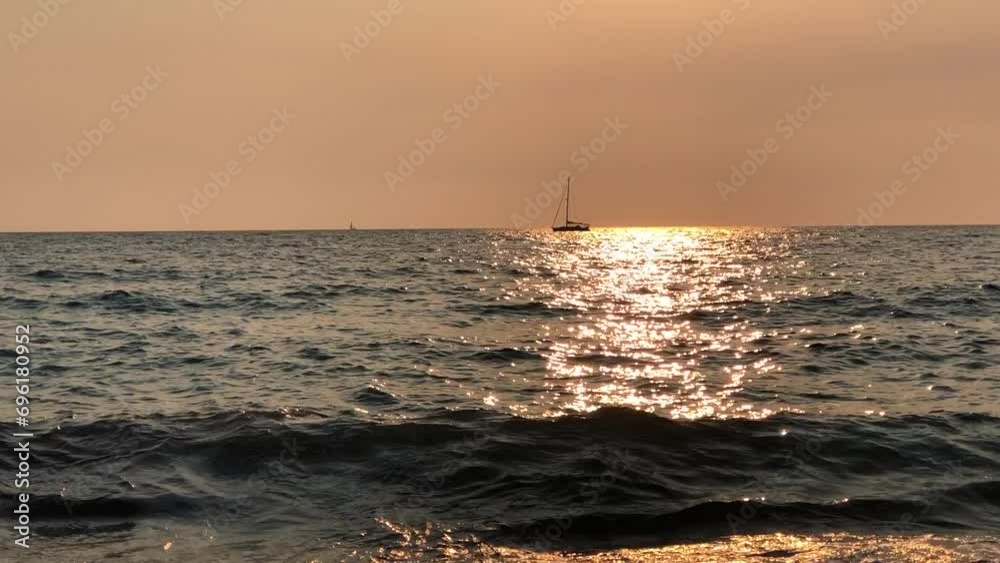 The silhouette of a yacht against the golden glare of the evening sun reflected in the sea. The silhouette of a yacht against the golden glare of the evening sun reflected in the sea.