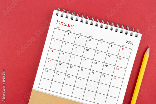 January 2024 desk calendar and pencil on red background.