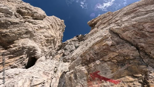 Climbers ascending a long Via Ferrata route to the top of Piz Ciavazes in the Dolomites, using steel cables and ladders on a steep rock wall. photo