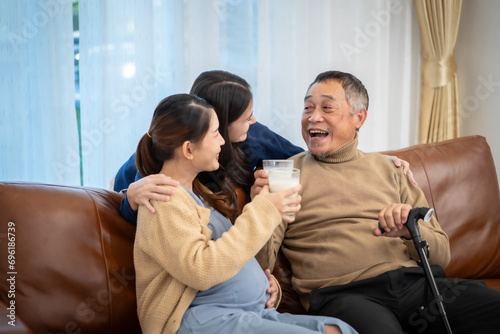 family father two pregnant daughter sitting together drink milk excited about having grandchildren