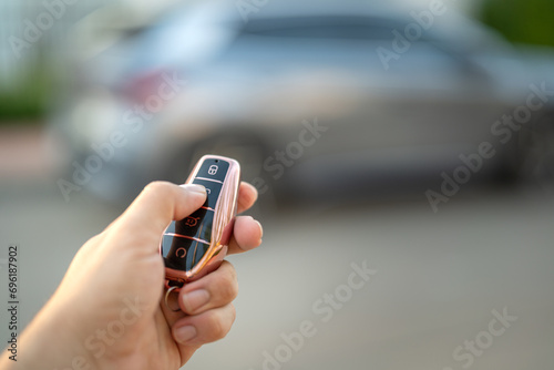 The driver hand is holding a keyless key to unlocking the car, photo with  luxury car as blurred background. Ready for driving concept scene. photo