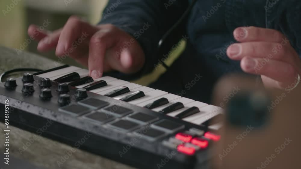 Close up of Caucasian musician creating music, playing MIDI keyboard and moving rhythmically while sitting in gazebo in forest. Adult man uses laptop and phone on tripod to record song outdoors. Close up of Caucasian musician creating music, playing MIDI keyboard and moving rhythmically while sitting in gazebo in forest. Adult man uses laptop and phone on tripod to record song outdoors.