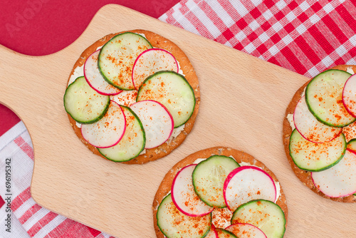 Light Breakfast or Diet Eating - Crispy Cracker Sandwich with Cream Cheese, Fresh Cucumber and Radish on Wooden Cooking Board on Magenta Background