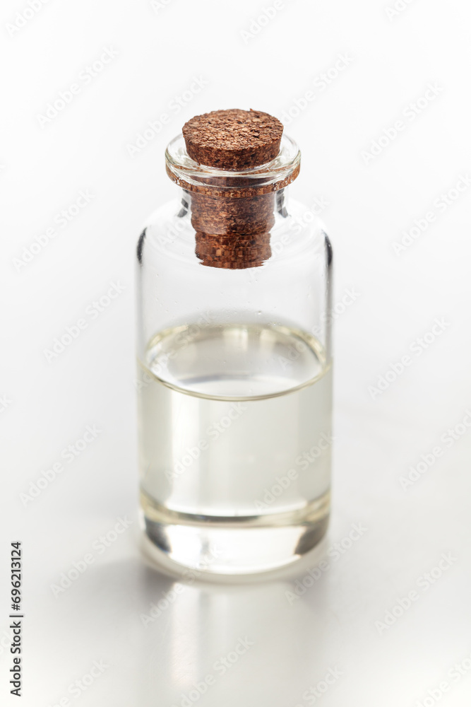 A round glass bottle containing clear transparent essential oil for cosmetics and natural medicine.