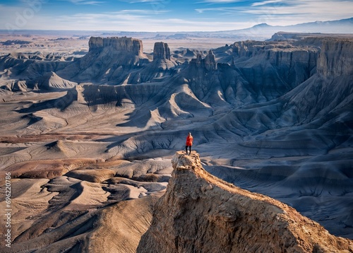Woman in red jacket on cliff above colorful canyon. Moonscape overlook. Hanksville. Utah. USA