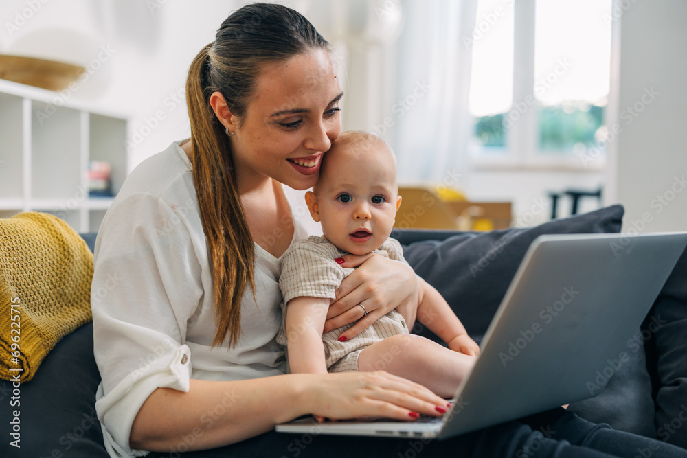 Happy mother is holding a baby and using laptop at home. Happy mother is holding a baby and using laptop at home.
