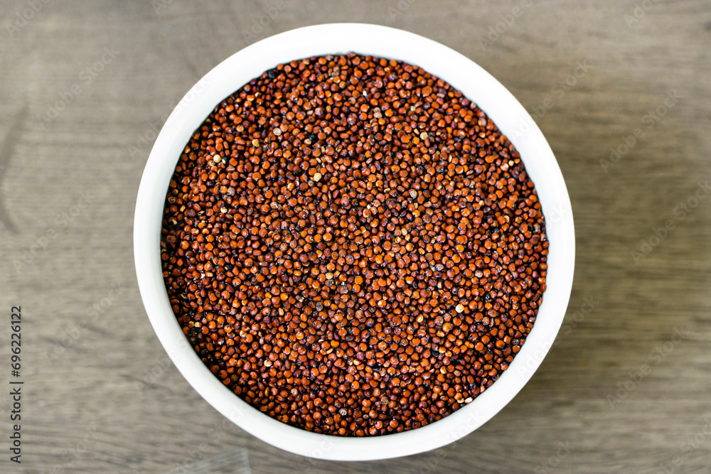 Red quinoa on the white plate on the wooden background. Healthy food and nutrition concept. Safe, ecological, and healthy products Red quinoa on the white plate on the wooden background. Healthy food and nutrition concept. Safe, ecological, and healthy products