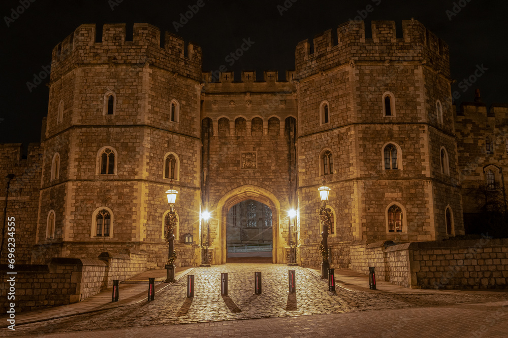 King Henry VIII gate private entrance secure stone fortified walls. Windsor Castle grounds lit at night. historic building in UK England royal home tourist attraction place of interest