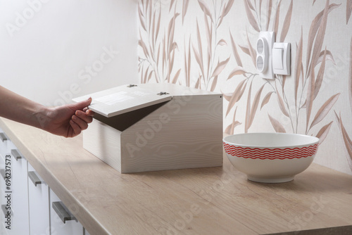 Woman opening wooden bread box on the kitchen counter photo