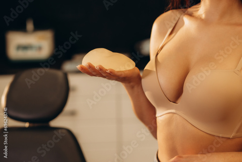 Woman planning to have a breast implant. Silicone implants on hand and natural breast photo