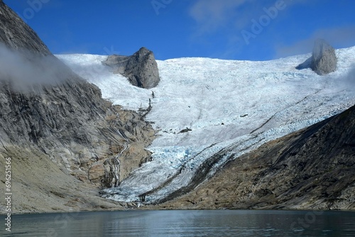 the sermeq glacier and rocky sprires
 at the end of the tasermuit fjord on a sunny summer day near nanortalik, in southern greenland photo