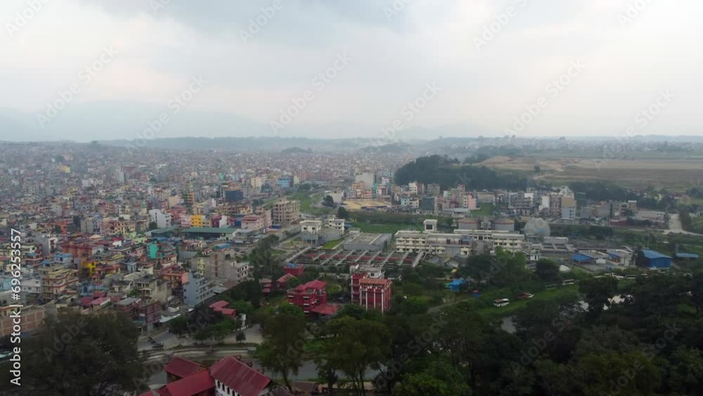 Drone push in above forest reveals dense urban Nepalese town with clouds above Drone push in above forest reveals dense urban Nepalese town with clouds above