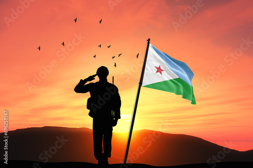 Silhouette of a soldier with the Djibouti flag stands against the background of a sunset or sunrise. Concept of national holidays. Commemoration Day. photo