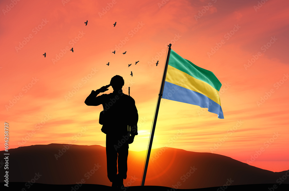 Silhouette of a soldier with the Gabon flag stands against the background of a sunset or sunrise. Concept of national holidays. Commemoration Day.