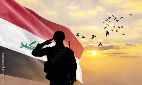 Silhouette of a soldier with the Iraq flag stands against the background of a sunset or sunrise. Concept of national holidays. Commemoration Day. photo