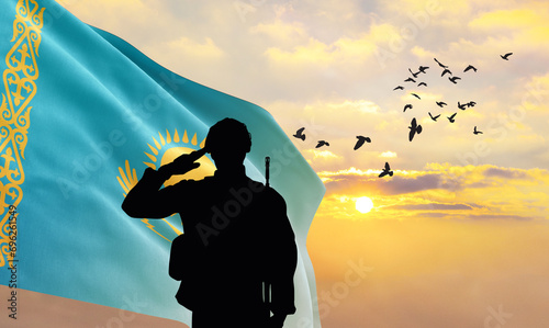 Silhouette of a soldier with the Kazakhstan flag stands against the background of a sunset or sunrise. Concept of national holidays. Commemoration Day. photo