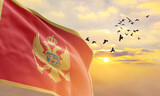 Waving flag of Montenegro against the background of a sunset or sunrise. Montenegro flag for Independence Day. The symbol of the state on wavy fabric.
