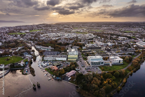 Aerial view on Galway city suburbs and river Corrib at sunset. Dramatic rich cloudy sky. Town high populated area. Irish landscape view. photo