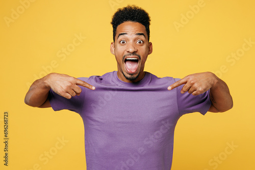 Принти на полотні Young overjoyed exultant man of African American ethnicity he wears purple t-shirt casual clothes point index fingers on himself isolated on plain yellow background studio portrait