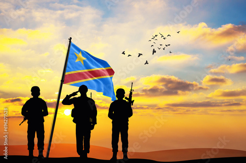 Silhouettes of soldiers with the DR Congo flag stand against the background of a sunset or sunrise. Concept of national holidays. Commemoration Day. photo