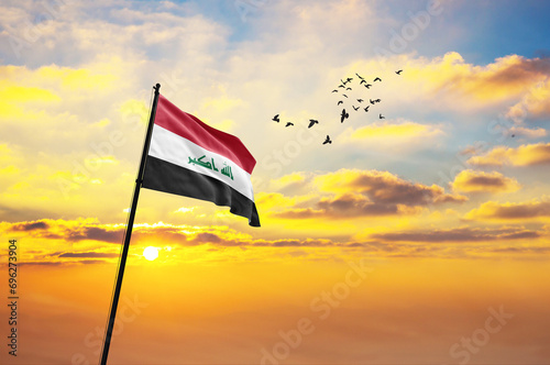 Waving flag of Iraq against the background of a sunset or sunrise. Iraq flag for Independence Day. The symbol of the state on wavy fabric.