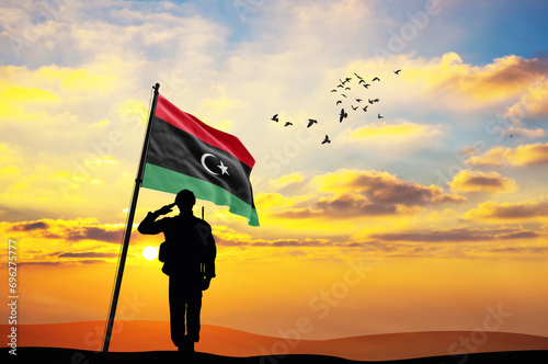 Silhouette of a soldier with the Libya flag stands against the background of a sunset or sunrise. Concept of national holidays. Commemoration Day.