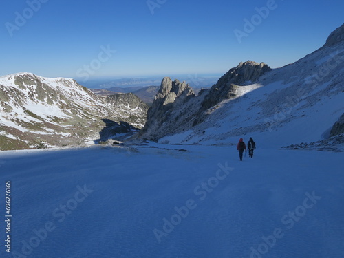 Randonnée en montagne avec des gens en alpinisme avec crampons et piolet en hiver sur la neige et la glace dans les Pyrénées © Ourson+