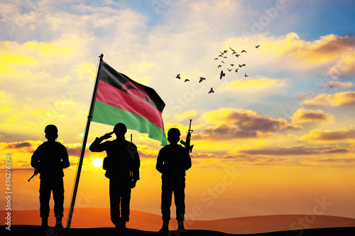 Silhouettes of soldiers with the Malawi flag stand against the background of a sunset or sunrise. Concept of national holidays. Commemoration Day. photo