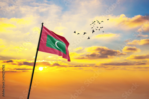 Waving flag of Maldives against the background of a sunset or sunrise. Maldives flag for Independence Day. The symbol of the state on wavy fabric. photo