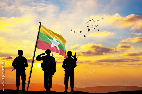 Silhouettes of soldiers with the Myanmar flag stand against the background of a sunset or sunrise. Concept of national holidays. Commemoration Day. photo