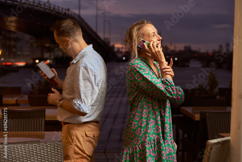 Adult joyful woman reports good news on the phone, a man's back is nearby in a city cafe.
