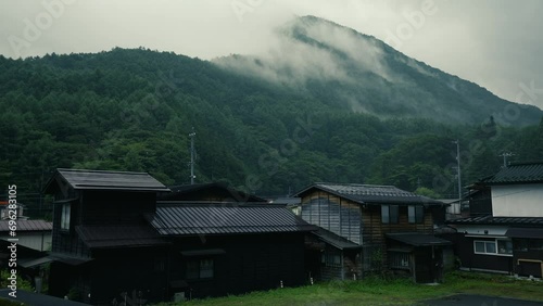 Houses in Japanese villages surrounded by nature White mist clouds cover the mountains during the rain.