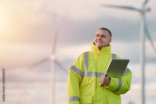Εκτύπωση καμβά A technician in a yellow jacket uses a tablet to monitor and install wind turbines and solar panels on a farm
