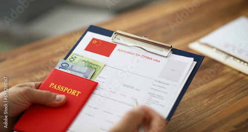 Male hand hold silver pen with passport. Filling China apllication form concept photo