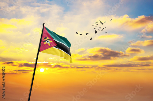 Waving flag of Mozambique against the background of a sunset or sunrise. Mozambique flag for Independence Day. The symbol of the state on wavy fabric. photo