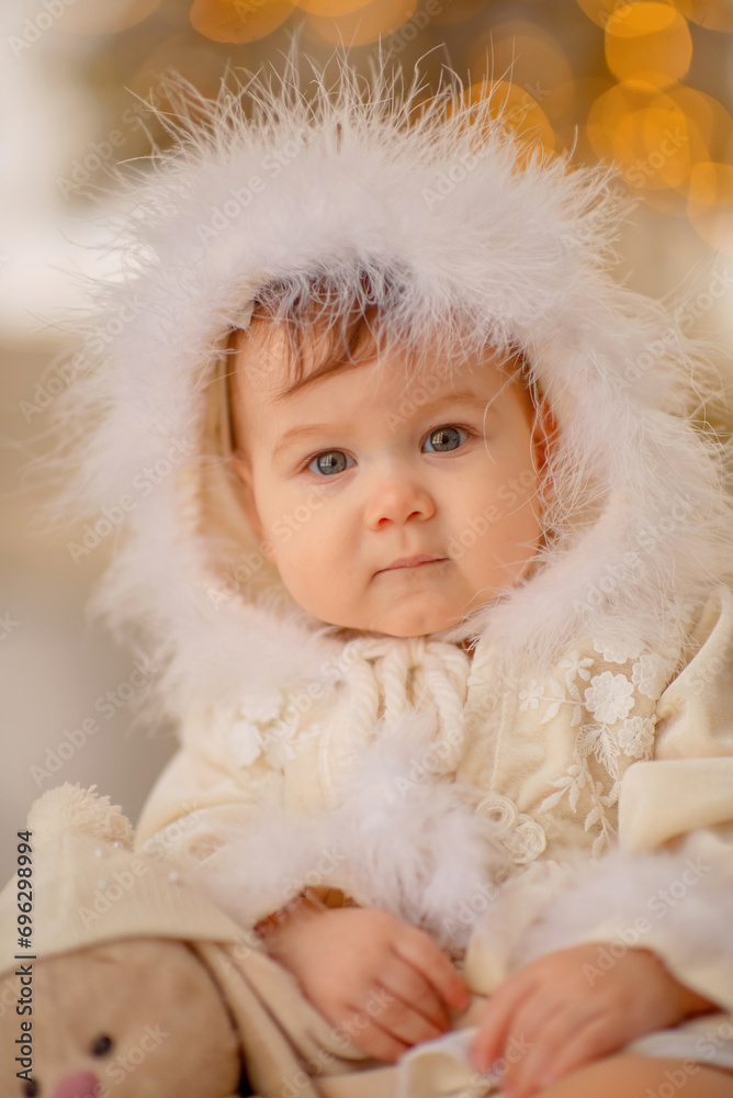 A small beautiful girl in a winter outfit sits on a sled. New Year. Christmas. The girl smiles. Decorated Christmas tree. Baby girl holding a bunny toy. Girl with a bow. Portrait. Winter. Lights A small beautiful girl in a winter outfit sits on a sled. New Year. Christmas. The girl smiles. Decorated Christmas tree. Baby girl holding a bunny toy. Girl with a bow. Portrait. Winter. Lights