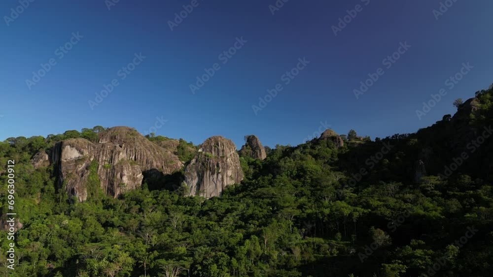 Aerial view of Nglanggeran Ancient Volcano in Gunungkidul, Yogyakarta, Indonesia with clear blue sky background. Rocky mountains with a lot of tree. Indonesian rainforest from above - 4k video footage Aerial view of Nglanggeran Ancient Volcano in Gunungkidul, Yogyakarta, Indonesia with clear blue sky background. Rocky mountains with a lot of tree. Indonesian rainforest from above - 4k video footage