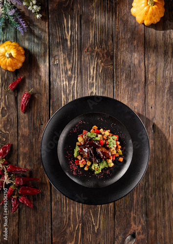 Beef cheeks with vegetable ratatouille, elegantly served on a dark plate, rustic top view photo