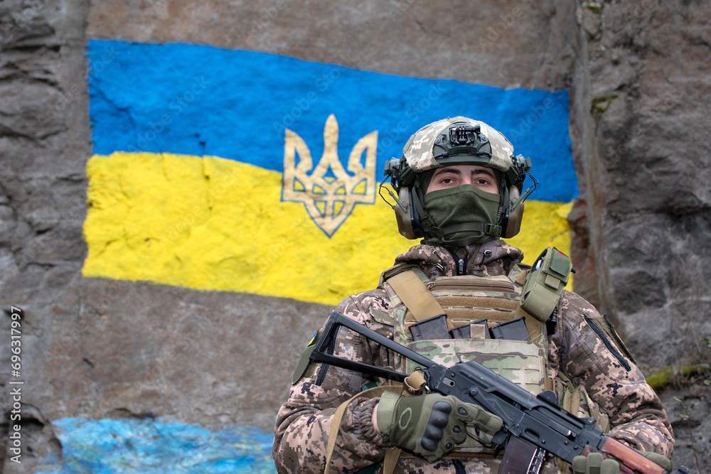 Ukrainian soldier against ukrainian flag painted on granite wall	