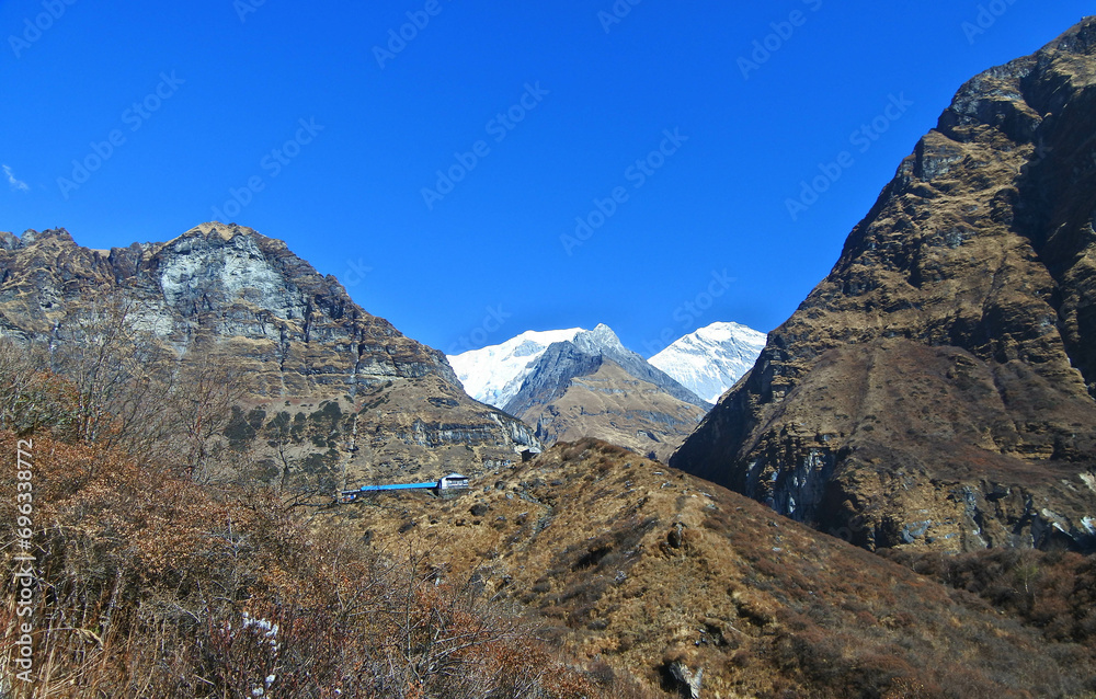 Stunning views of snow mountains, blue skies and large rocks along the track to ABC