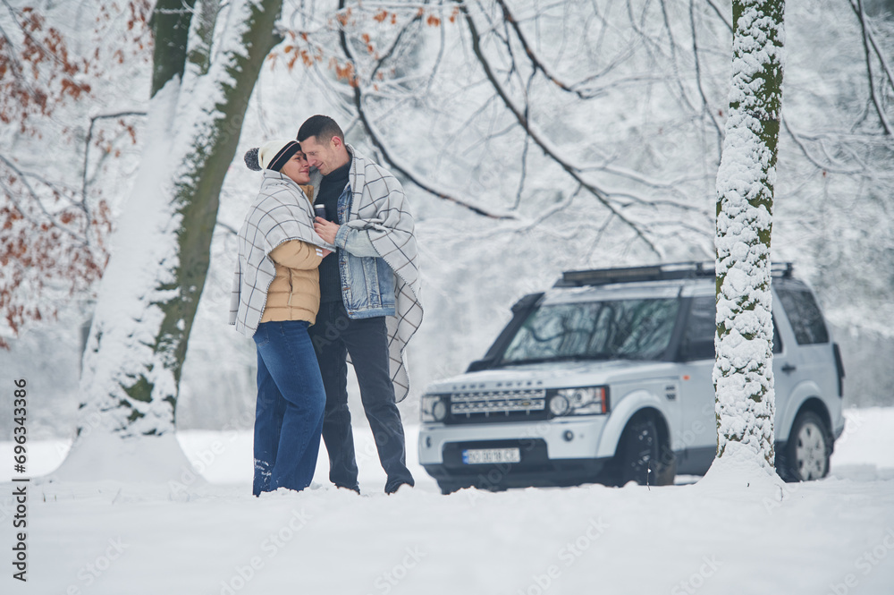 Beautiful nature. Couple is standing near the car in the winter forest