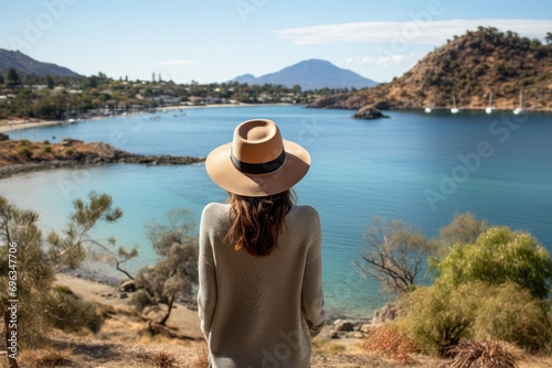 A woman wearing a hat looking out over a lake © pham