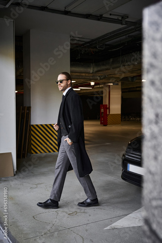 handsome man in elegant smart attire with sunglasses walking on parking lot, business concept