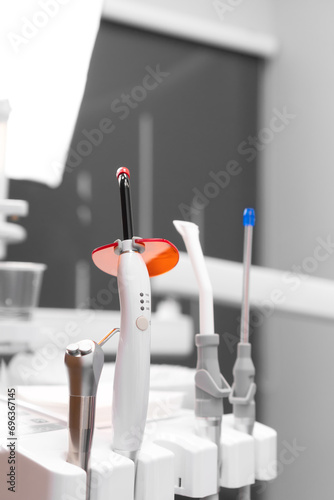 Close-up of dental instruments in the dentist's office, selective focus. Polymerization lamp, a saliva pump, a device for supplying water and air. Vertical photo