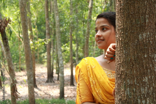 Young Indian girl hiding behind the tree. Portrait of young Indian girl behind the tree in park. Full face of girl behind tree.